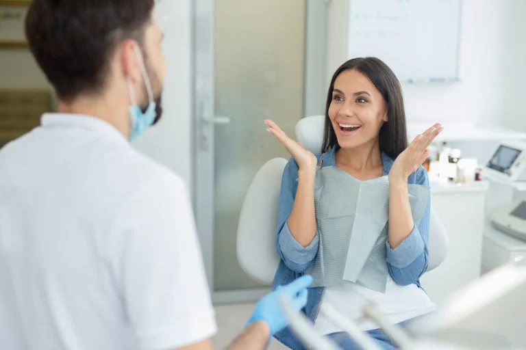 Woman gesturing near dentist talking to her in clinic